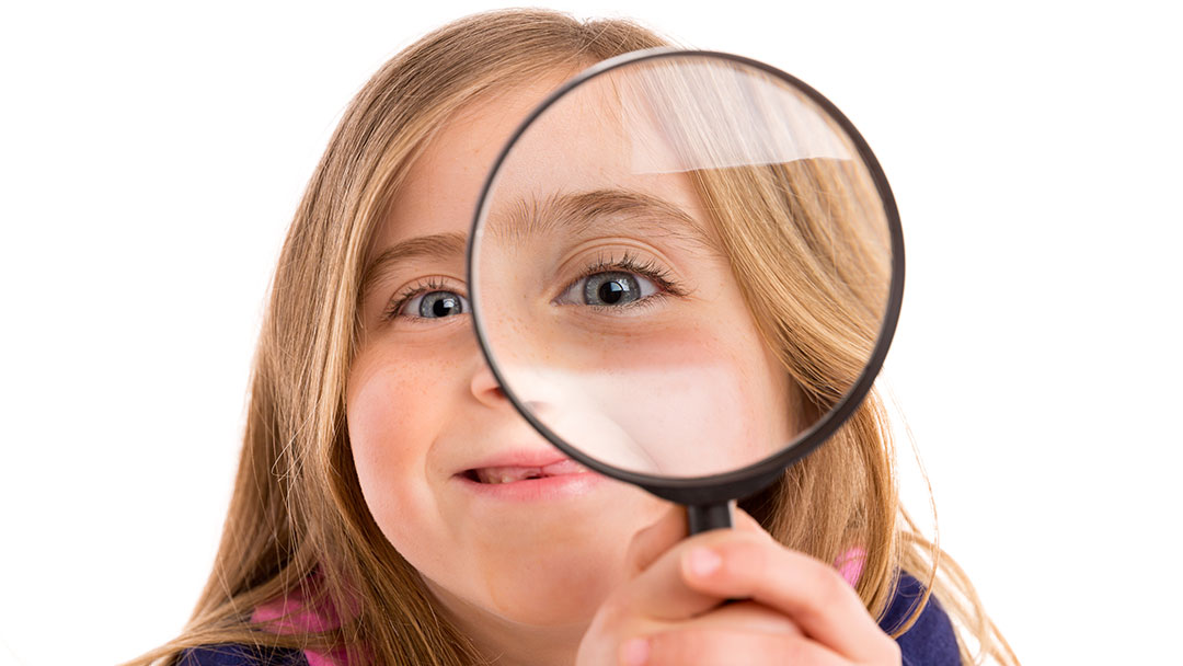 child with magnifying glass developing curiosity and growth mindset