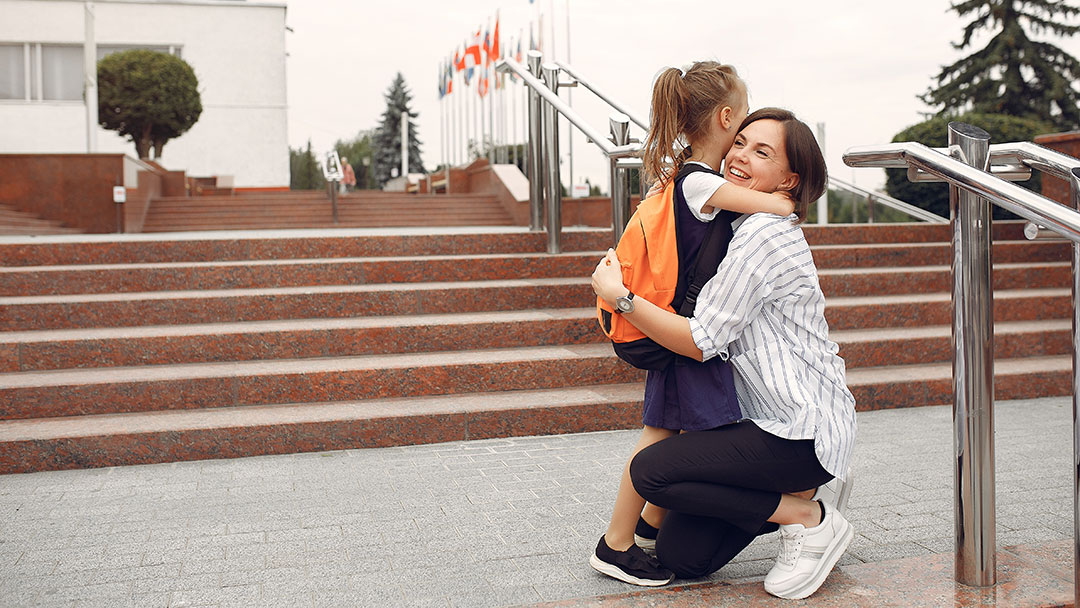 Mother hugging daughter on steps changing schools